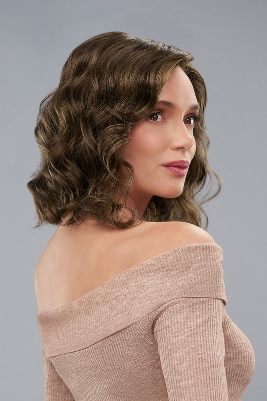 Woman with styled hair wearing an off-shoulder top against a gray background
