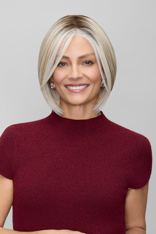 Woman with a styled haircut wearing a burgundy top against a plain background
