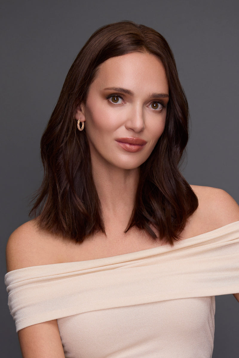 Woman wearing an off-shoulder beige top against a dark background