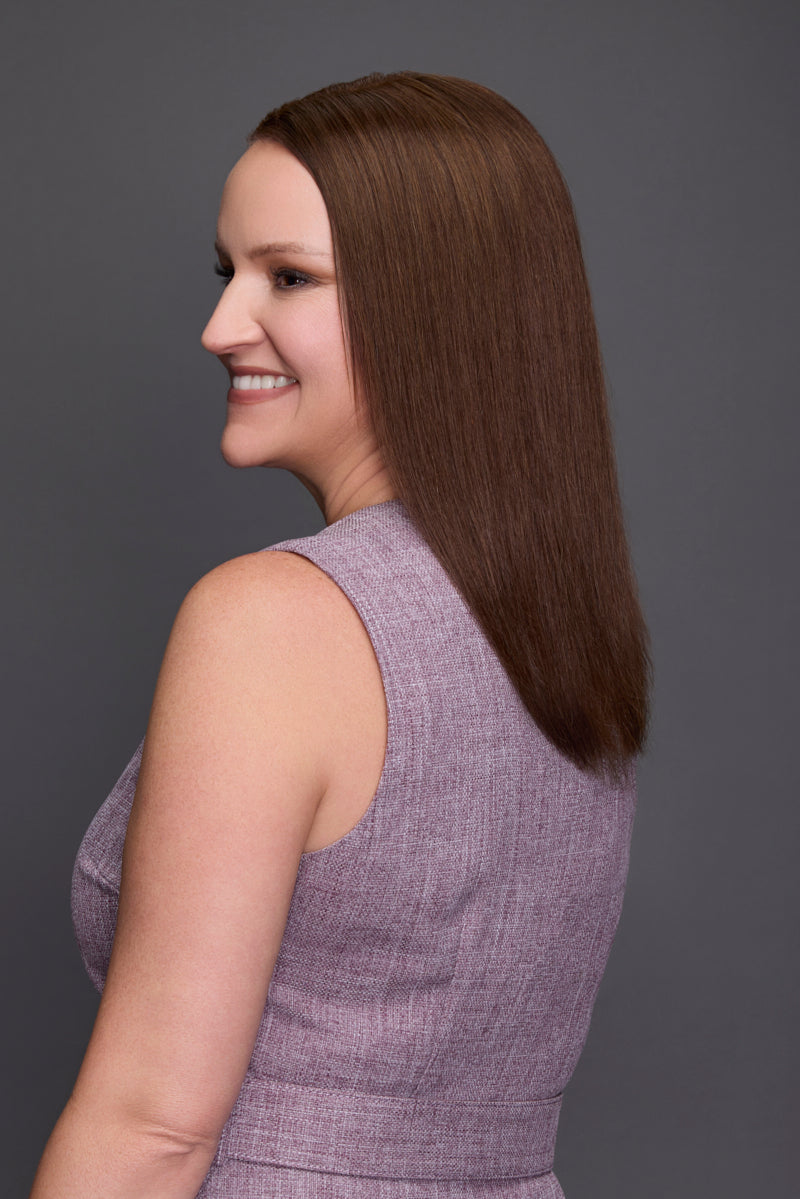 Woman with long brown hair wearing a purple dress against a gray background