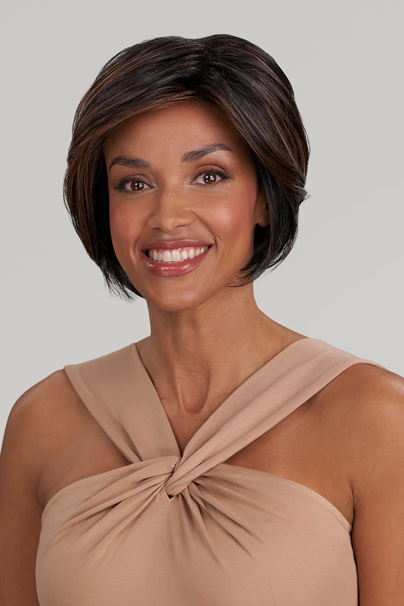Woman with a short, styled haircut wearing a beige top against a plain background
