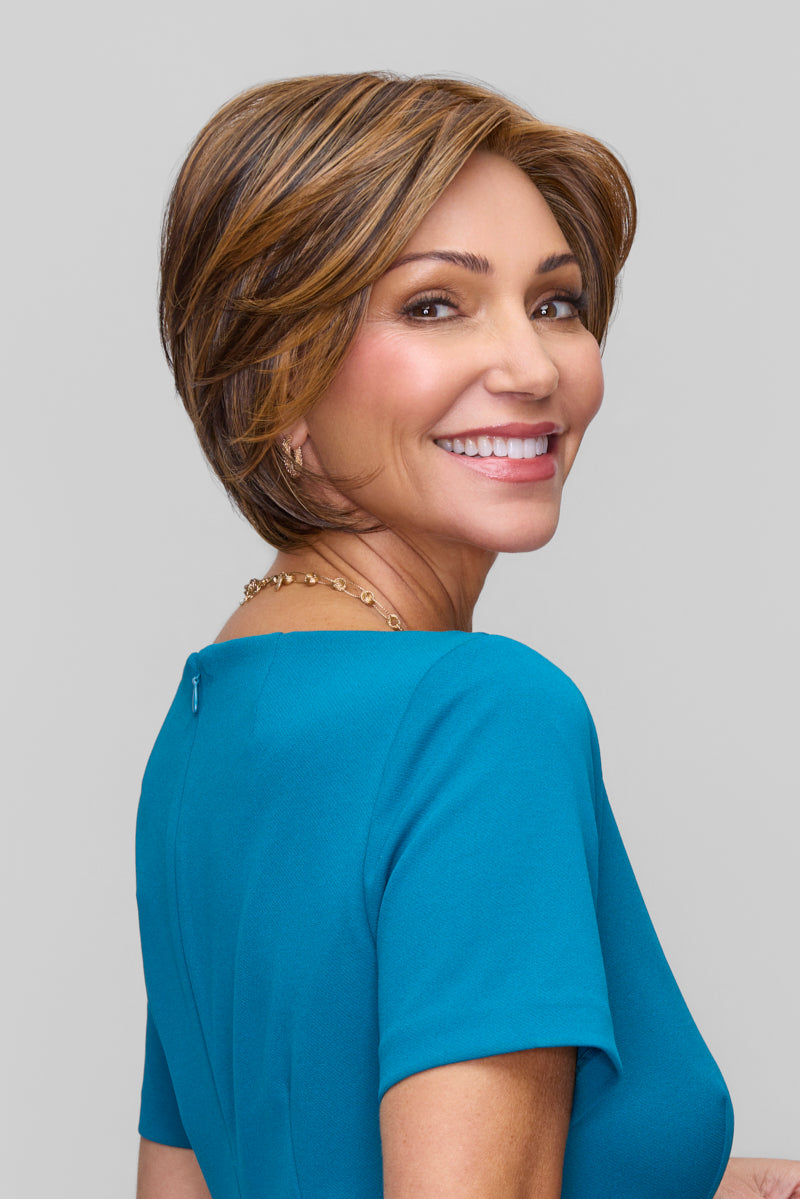 Woman with a short, styled haircut wearing a blue top against a plain background