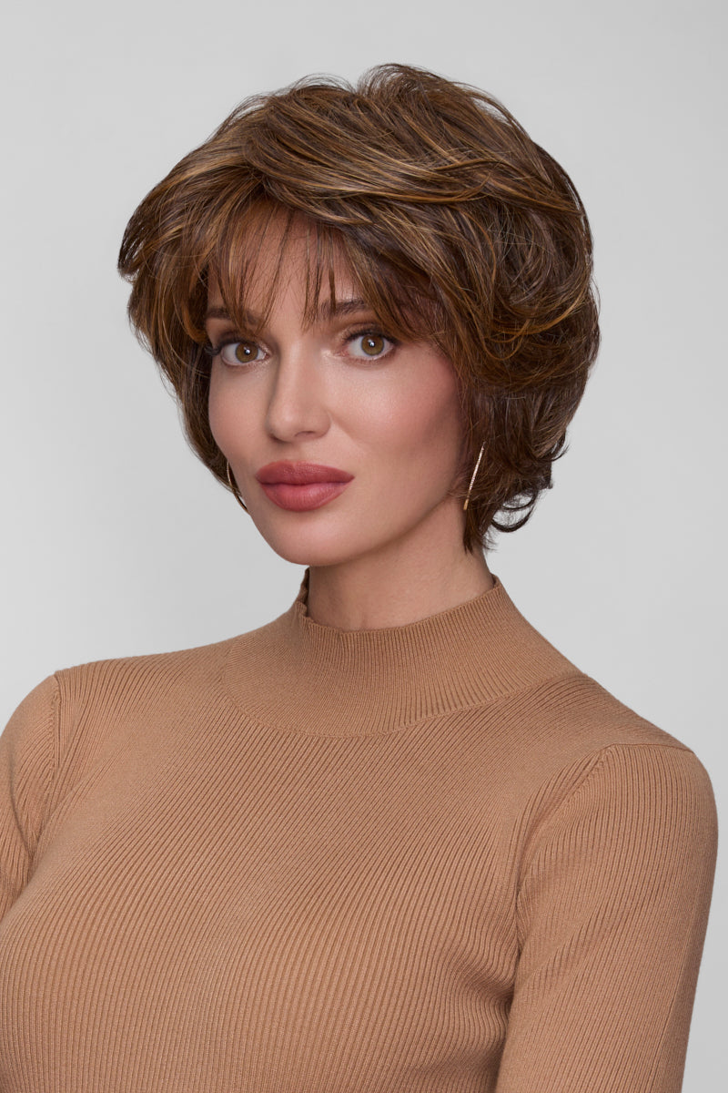 Woman wearing a brown wig against a plain background