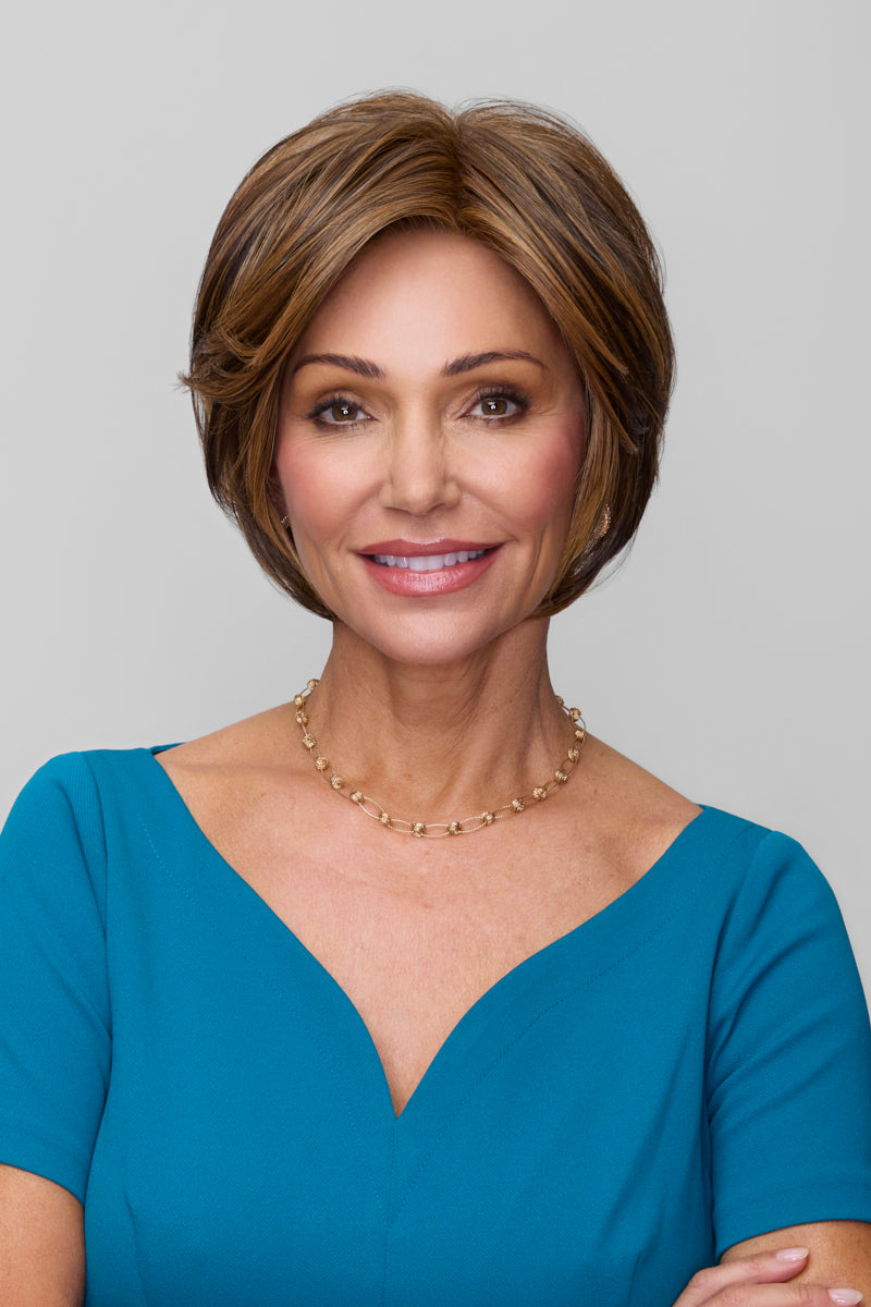 Woman with short brown hair wearing a blue dress against a gray background