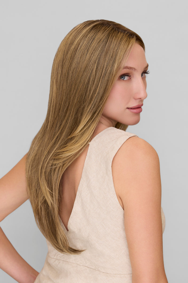 Woman with long blonde hair wearing a beige dress against a plain background