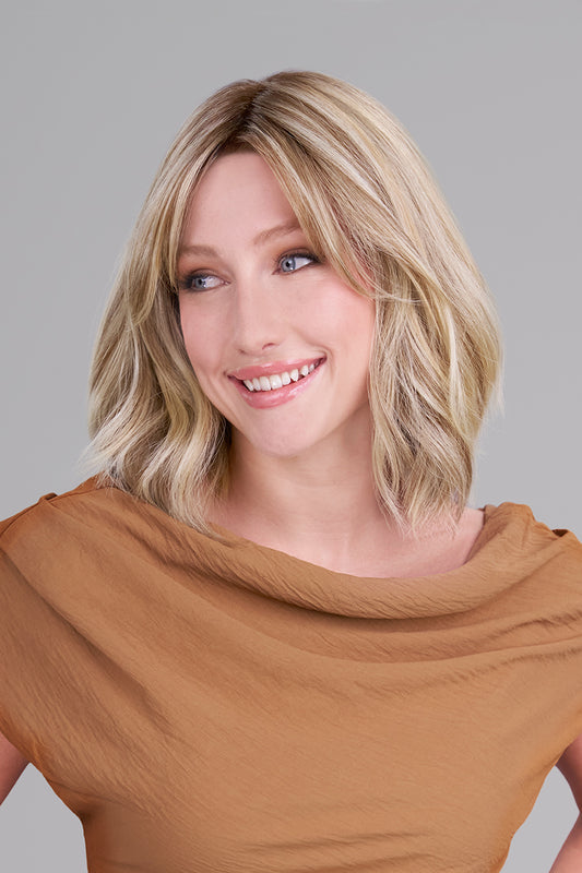 Woman with shoulder-length blonde hair wearing a brown top against a gray background