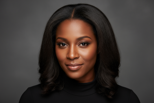 A headshot of a poised African American woman with a discerning eye wearing a black top with kinky straight hair